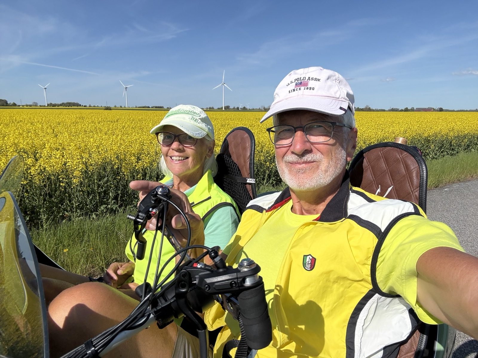 The couple cycling their recumbent trikes past a bright yellow rapeseed field